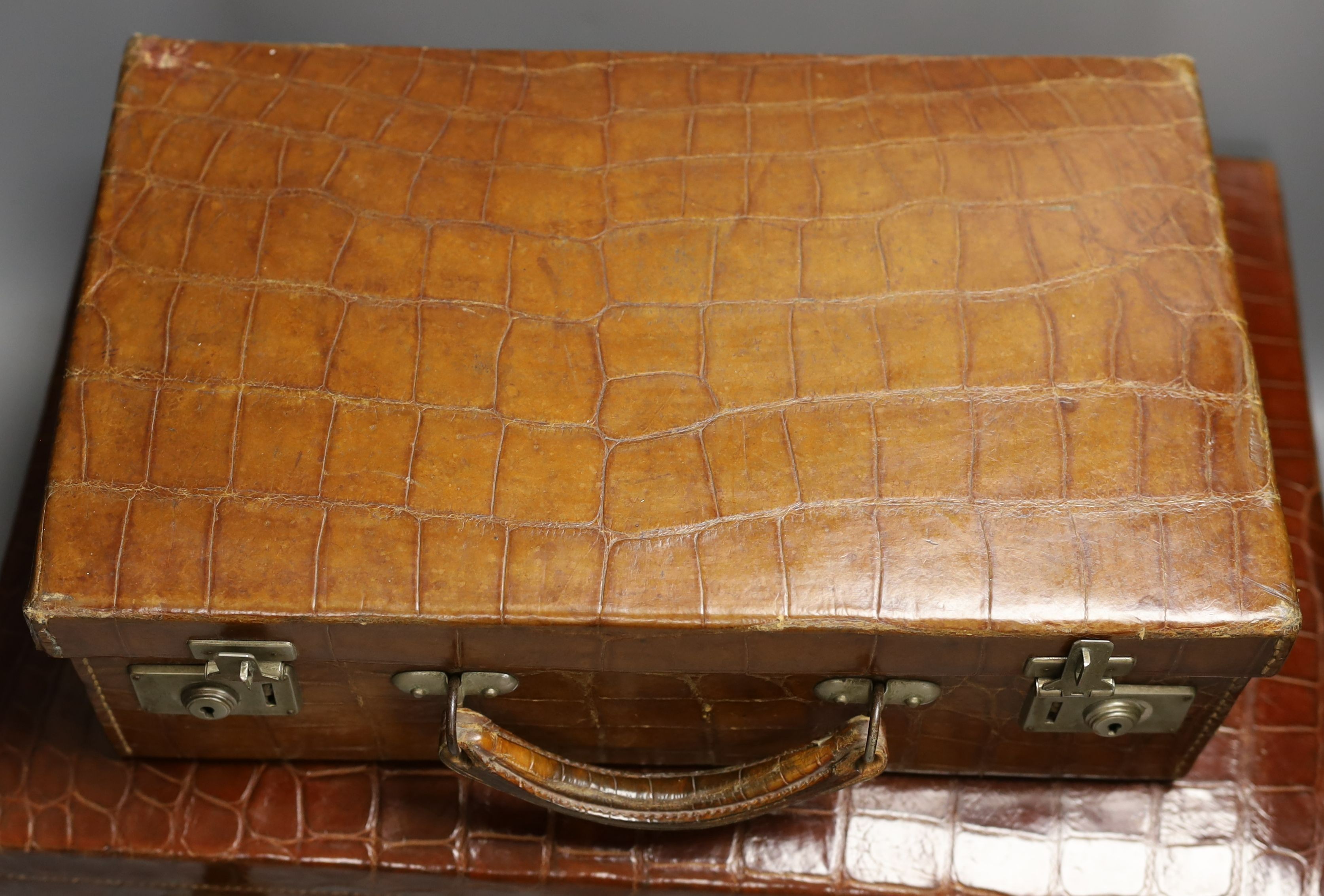 Two early 20th century crocodile hide suitcases, largest 48cms wide x 33 cms deep x 19cms high.